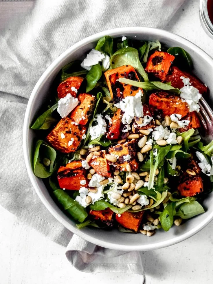Feldsalat mit Feta, gerösteter Süßkartoffel und Pinienkernen auf einem Teller