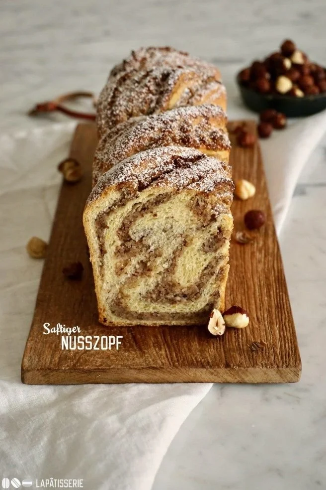 Saftiger Nusszopf mit nussiger Füllung auf einem Holzbrett