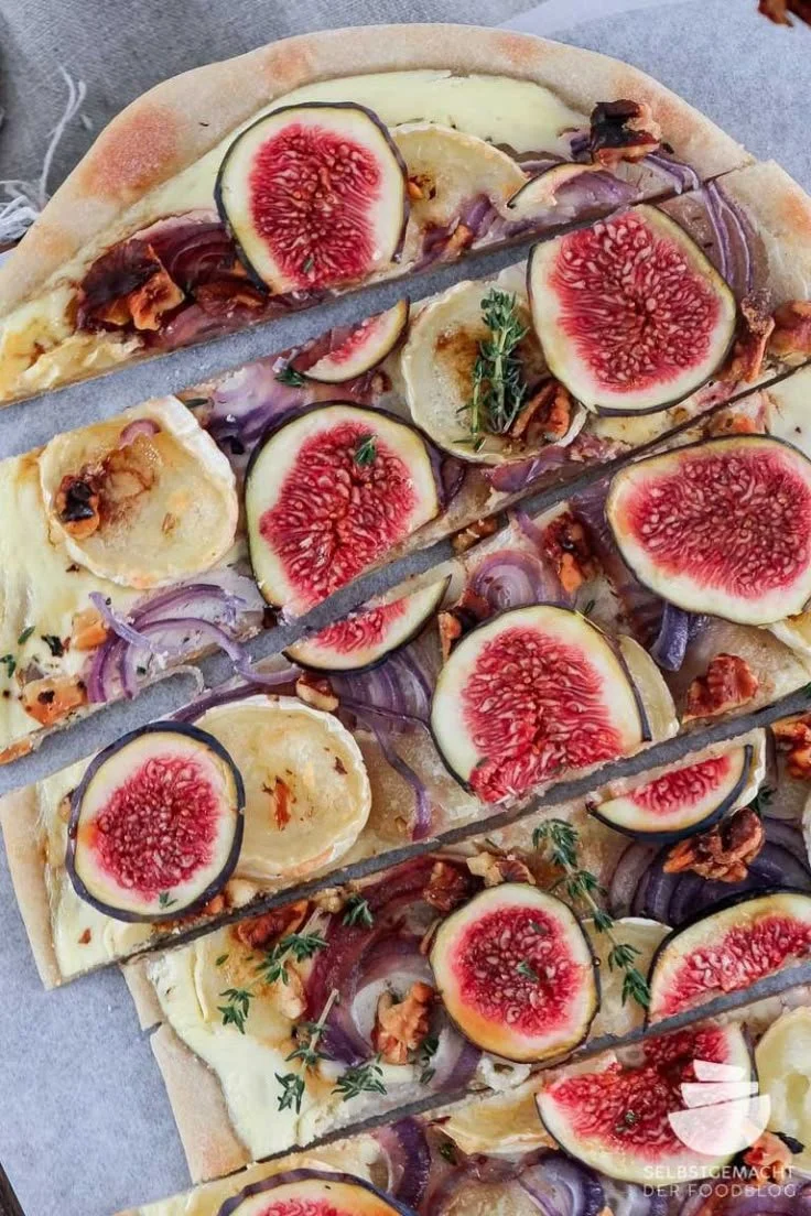 Vegetarischer Flammkuchen mit Feigen und Ziegenkäse auf einem Tisch serviert.